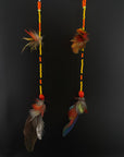 Two feathered earrings with beads on a black background