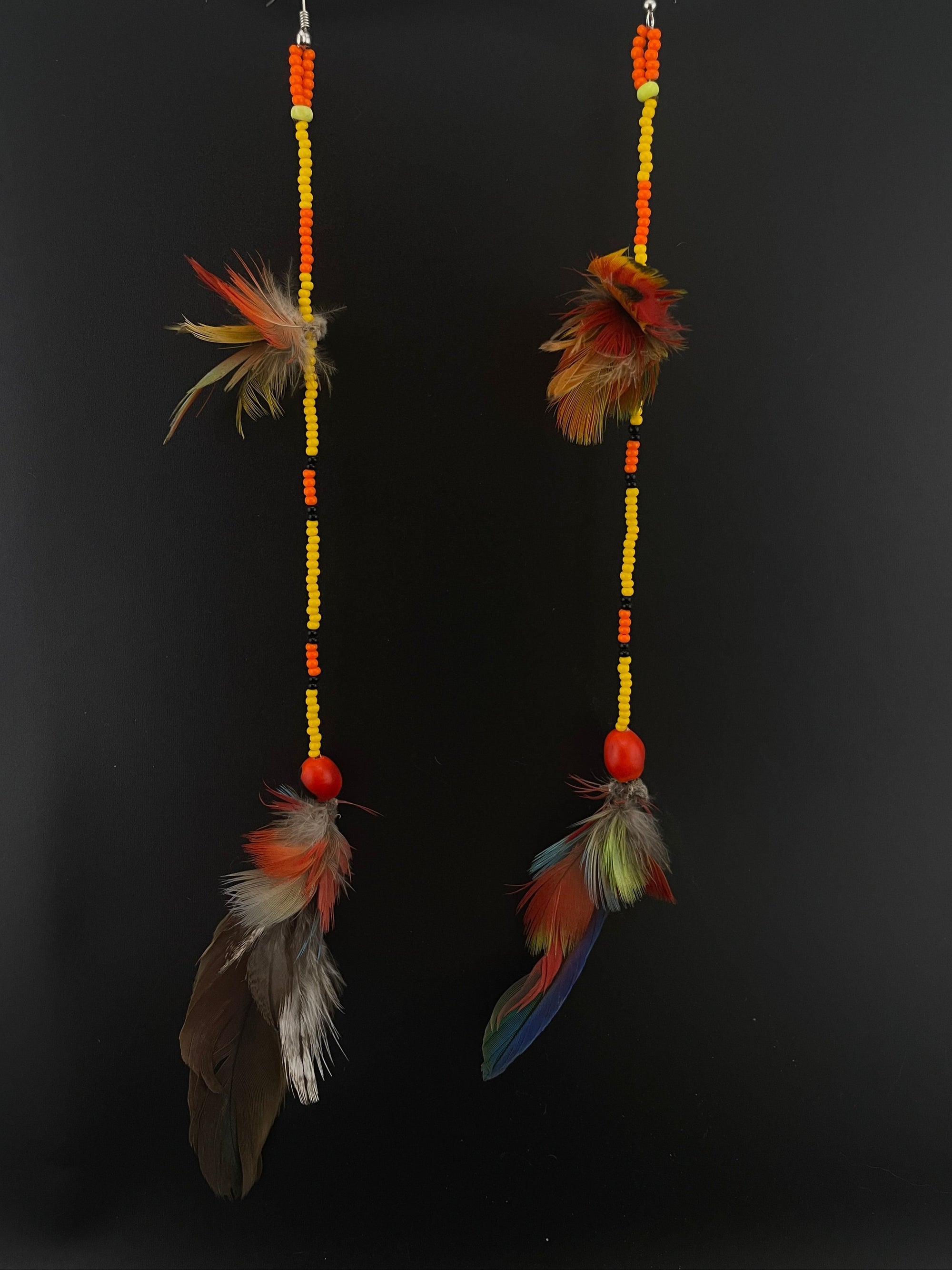 Two feathered earrings with beads on a black background