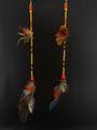Two feathered earrings with beads on a black background