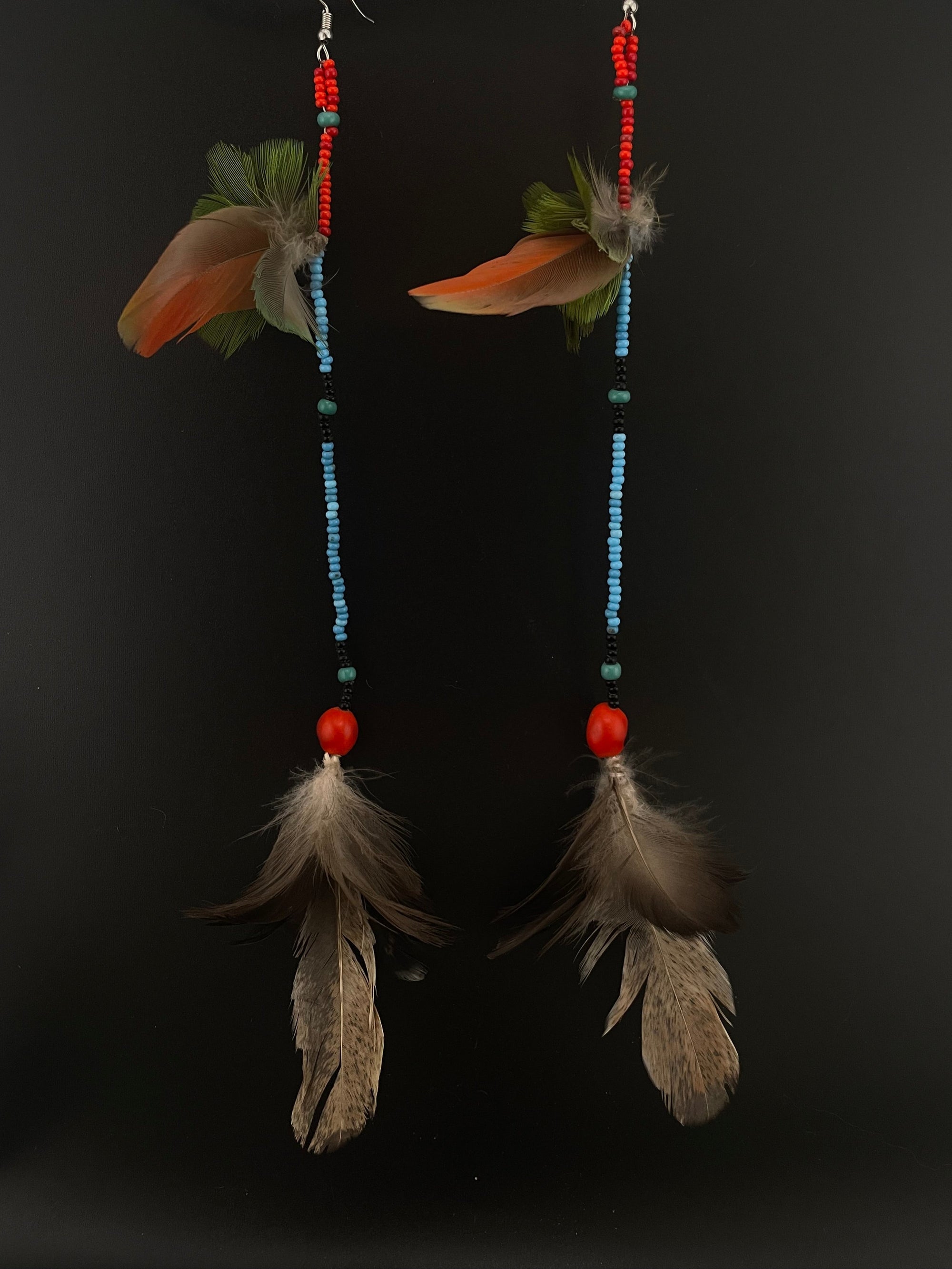 Pair of earrings with beads and feathers on a black background