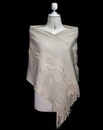 Beige shawl with fringe on a mannequin against a black background